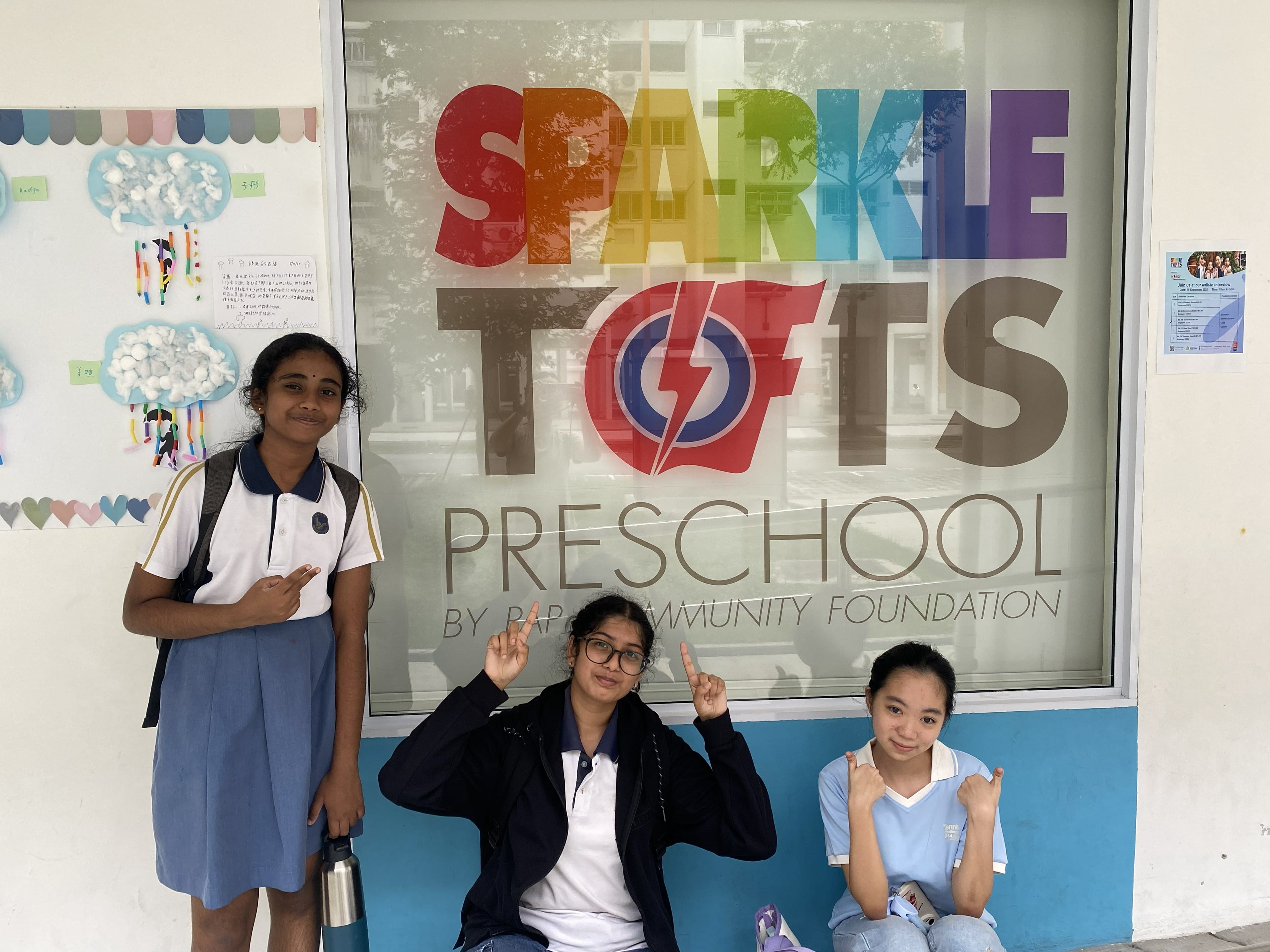 Three students posing outside a preschool